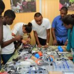 The STEM Guyana team giving Minister of Public Telecommunications, Ms. Catherine Hughes (first, right) a demo of their project